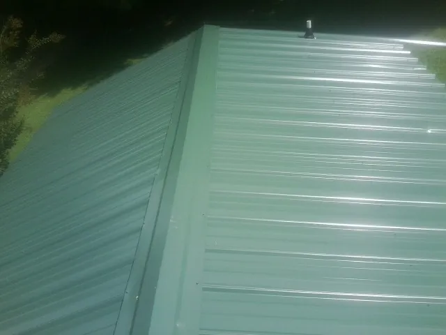 New green metal panels meeting at the ridge of a roof — Flat Roof Repair work by our crew in Scottsville