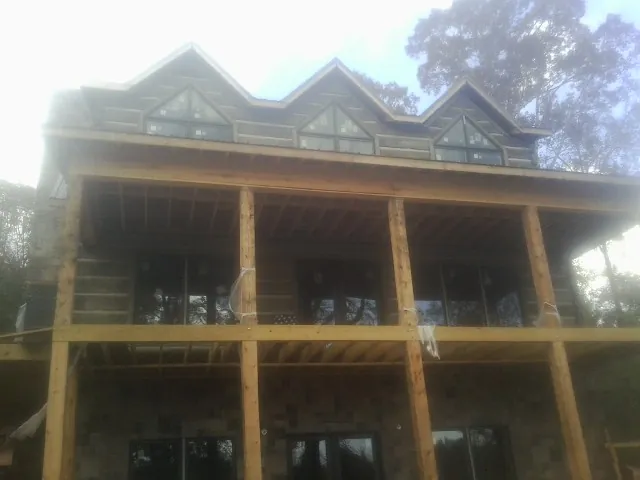 Dormers and porch framing on a large log home under construction — Roof Coating work by our crew in Scottsville