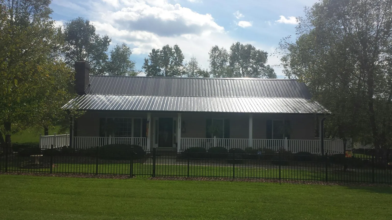 Gray metal roof on a brick ranch with a full width front porch — Gutter Guard Installation work by our crew in Scottsville