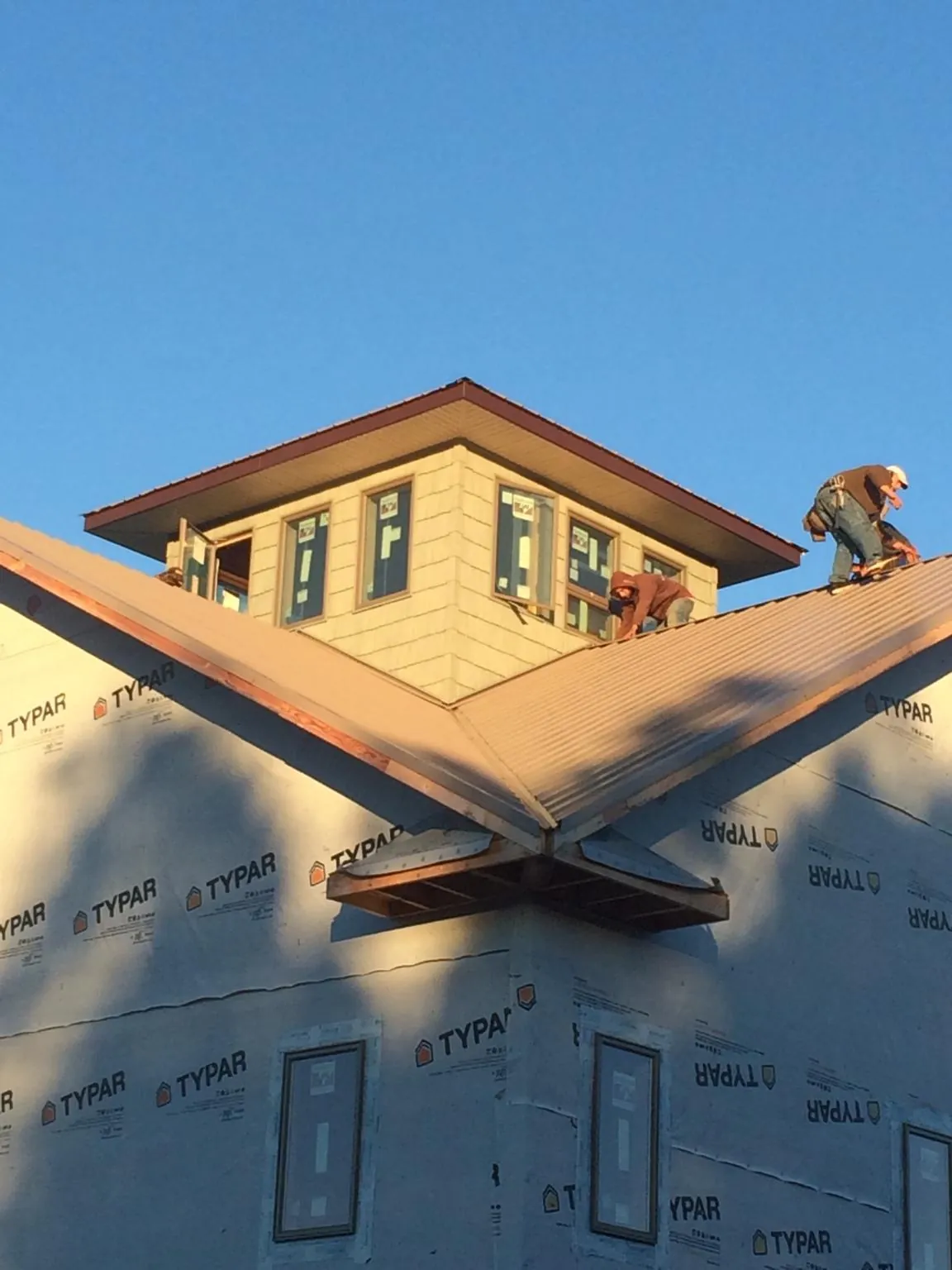 Roofers working around a rooftop cupola on a new metal roof at sunset — Roof Waterproofing in Scottsville by Roofing Brothers